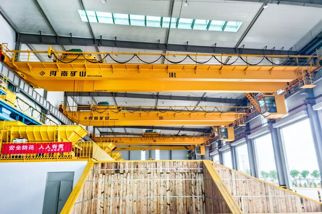Yellow overhead cranes operating above a customer workshop