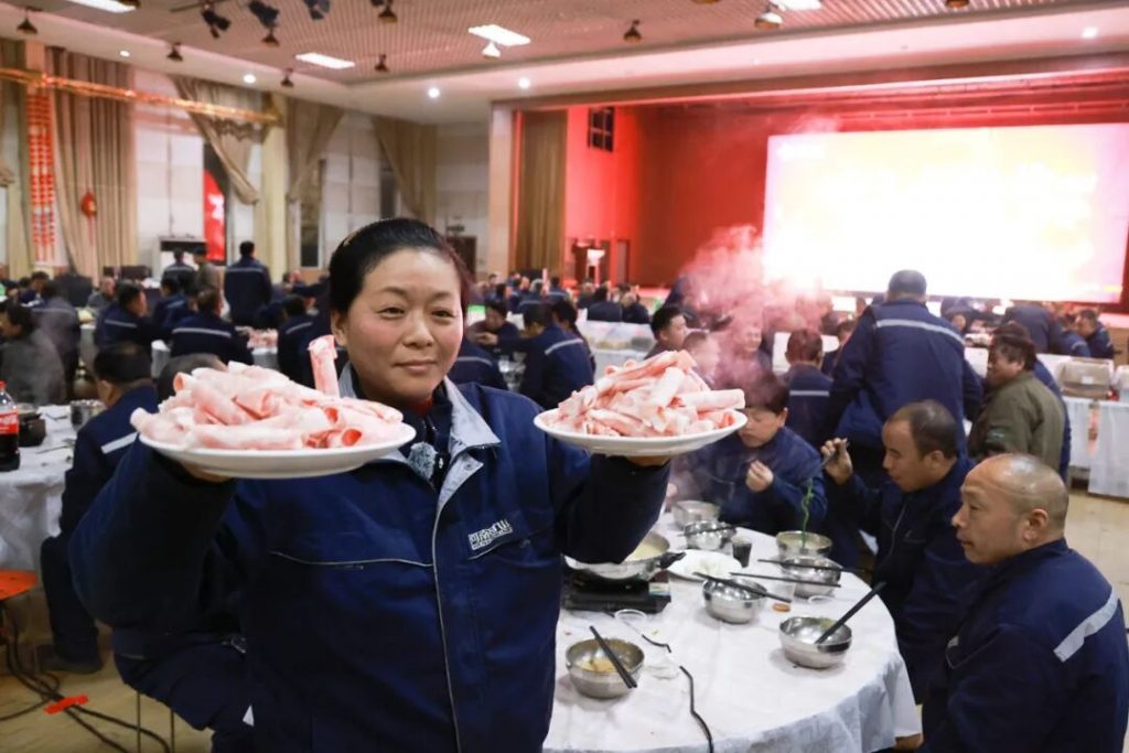 Employee carrying plates of meat through the dining hall