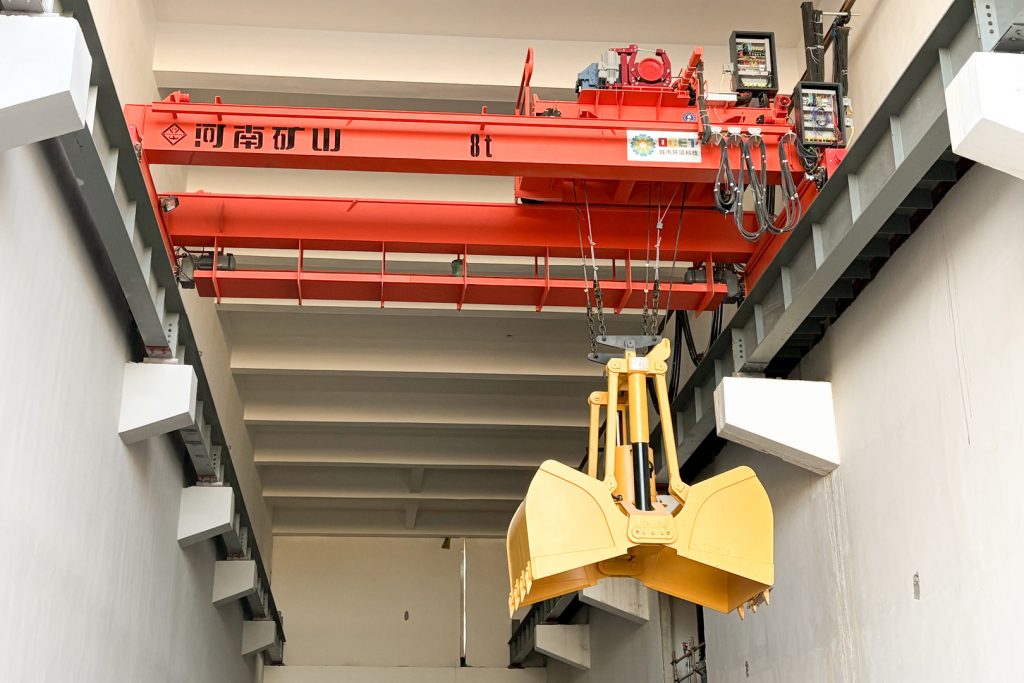 Red automatic grab crane above a waste storage bunker