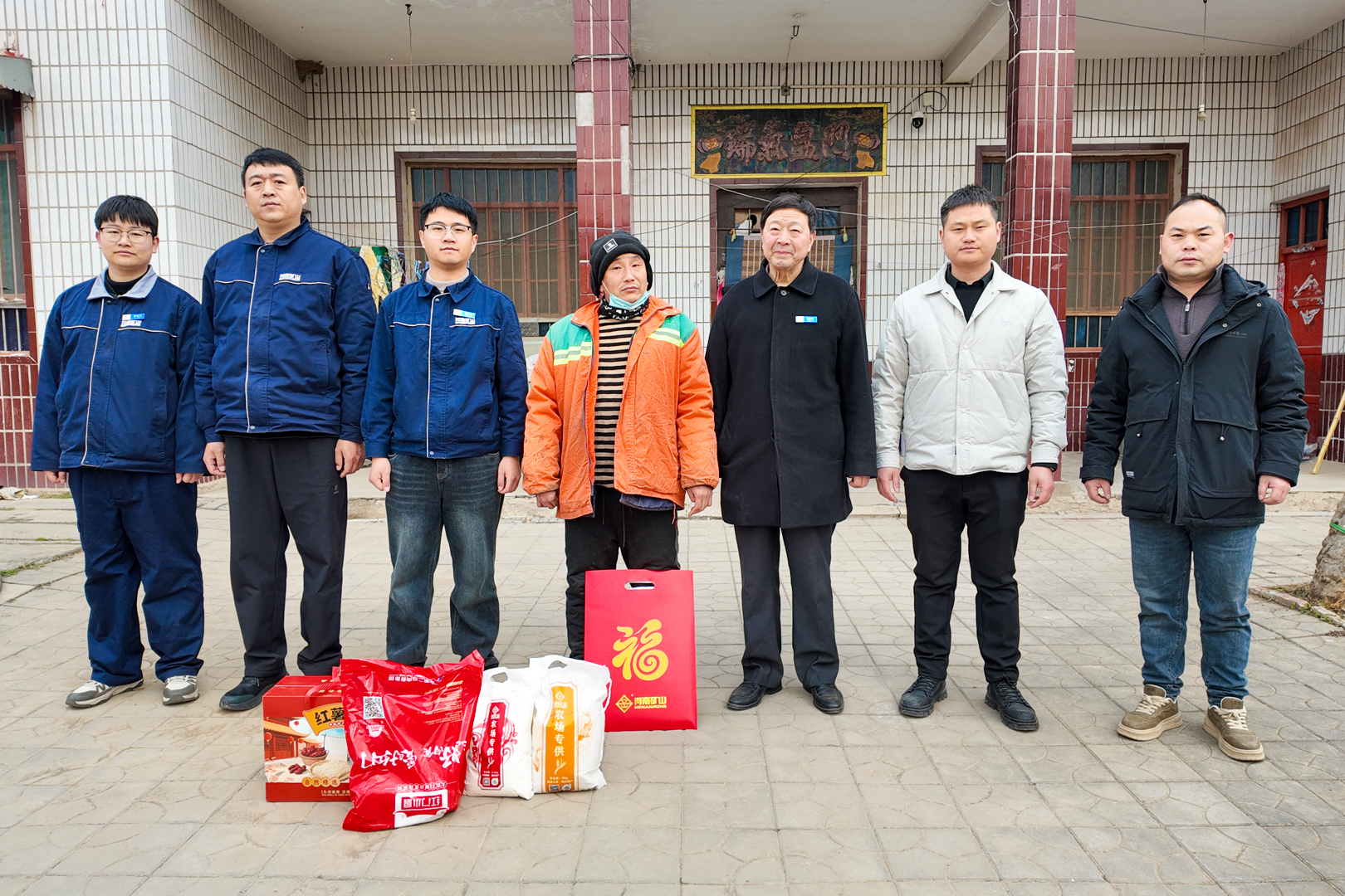 Representatives and residents with gifts outside a home during Henan Mine Crane’s New Year outreach