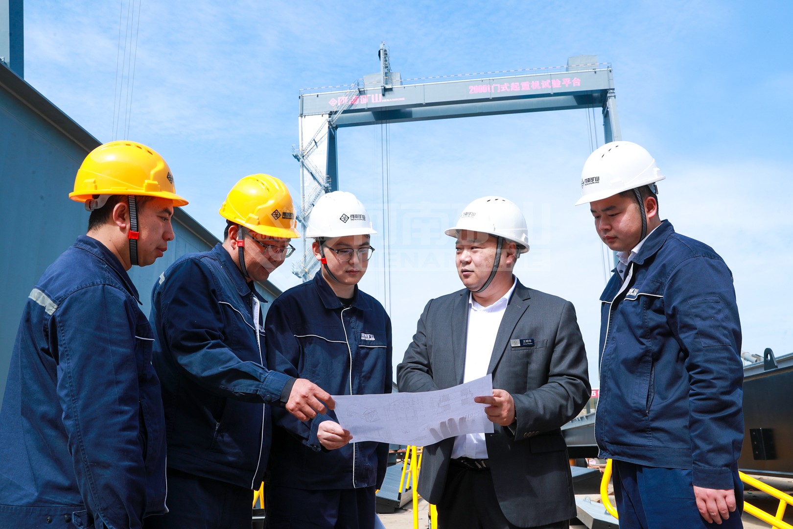 Inspectors reviewing drawings beside outdoor crane equipment