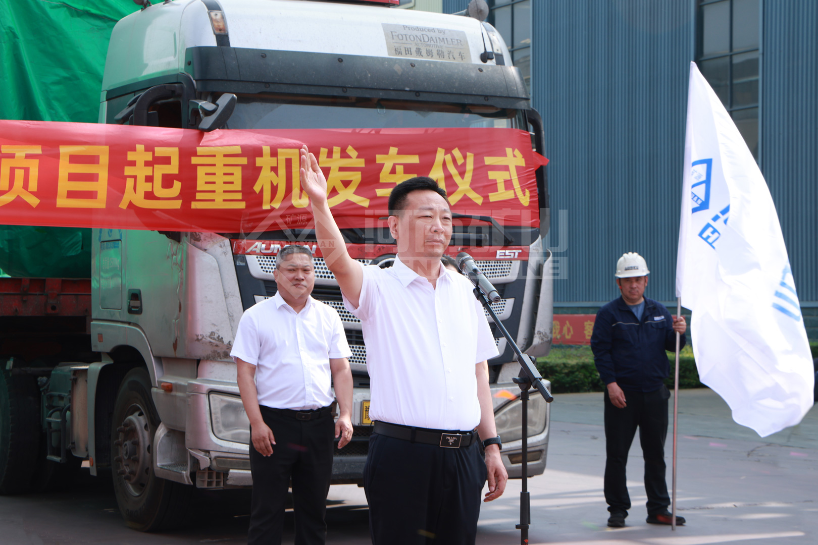 Representatives beside a covered equipment transport truck