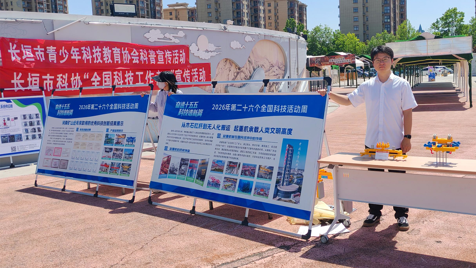 Science-week volunteers beside public information displays