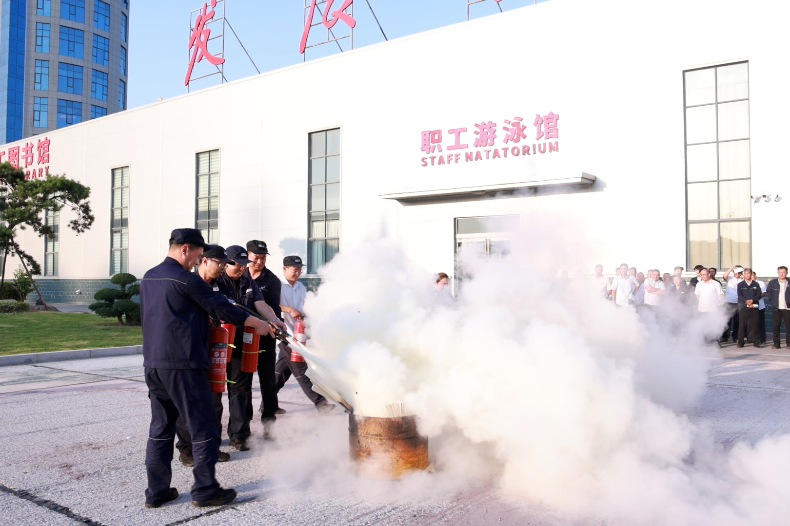 Employees practising fire-extinguisher use outside the workshop